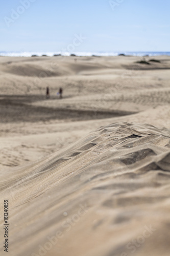 Sand dunes with tracks of pedestrians all over, blue ocean in the background