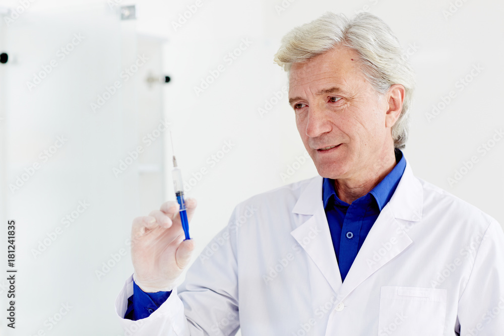Grey-haired clinician prepareing syringe with medicine for injection Grey-haired clinician prepareing syringe with medicine for injection