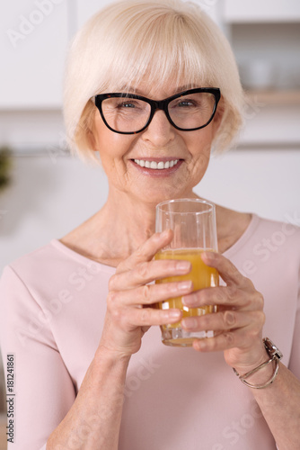 Portrait of a cheerful elderly woman drinking juice