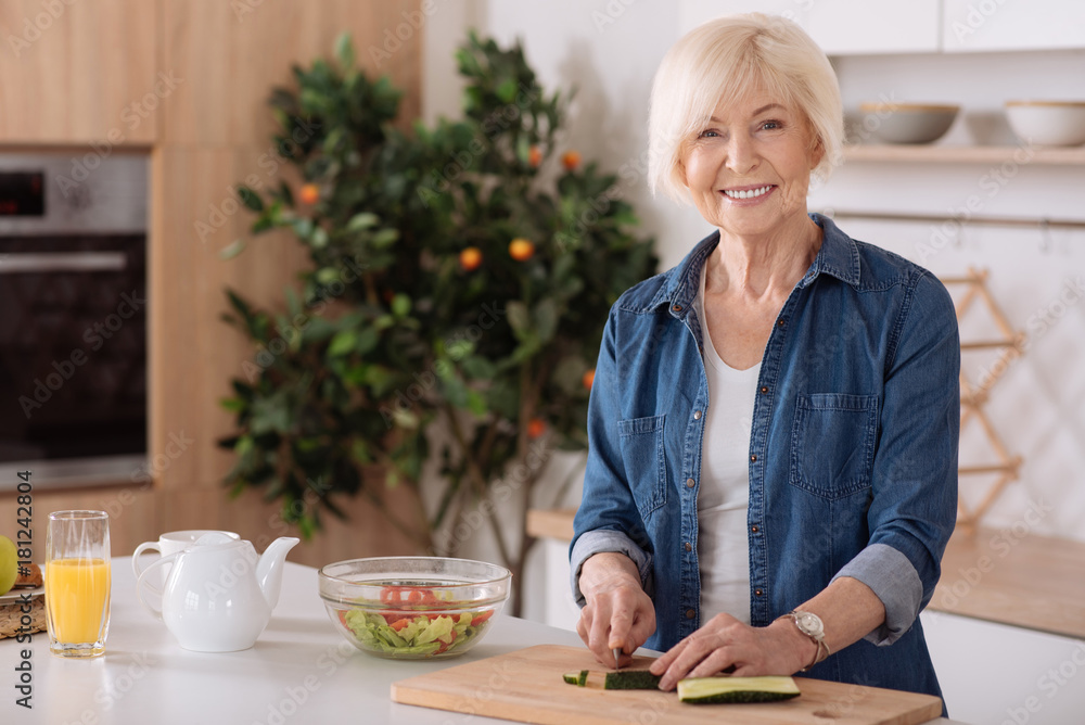 Smiling senior woman cooking a vegetable salad