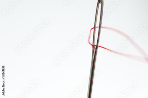 Needle eye close up shot , red thread, isolated on white background.