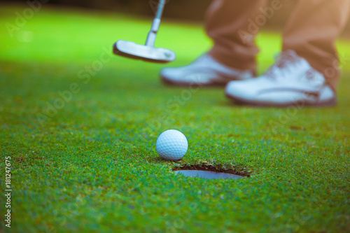 The golfers are hitting the golf ball into the hole.