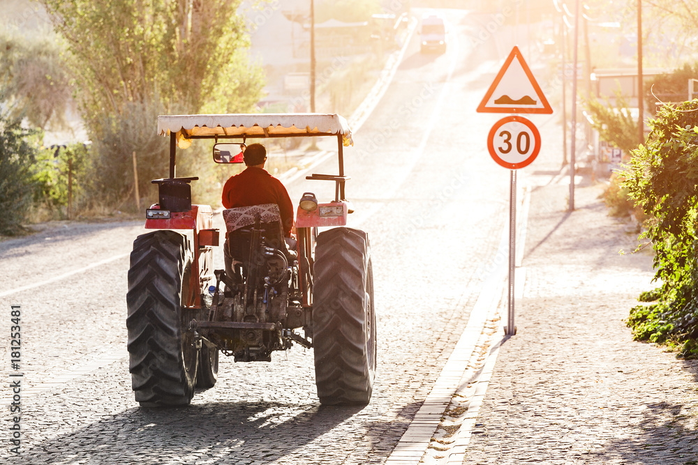Fototapeta premium Tractor rides on the pavement road in the sunlight