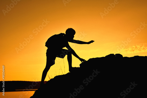 Silhouette of man hiking to the top mountain at sky sunset