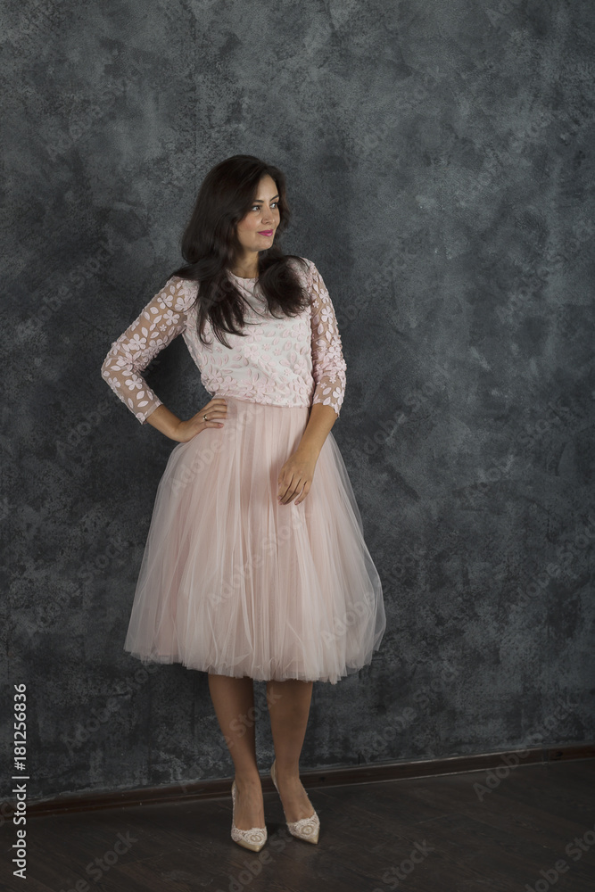 Young girl in a pink dress. Dark blue background. She looks away. Hand at waist. Young girl in a pink dress. Dark blue background. She looks away. Hand at waist.