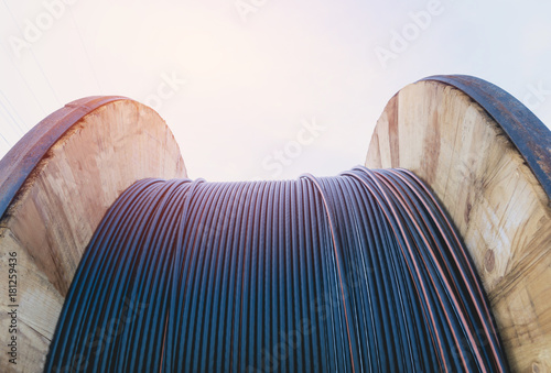 black wire electric cable with wooden coil of electric cable under the sky.