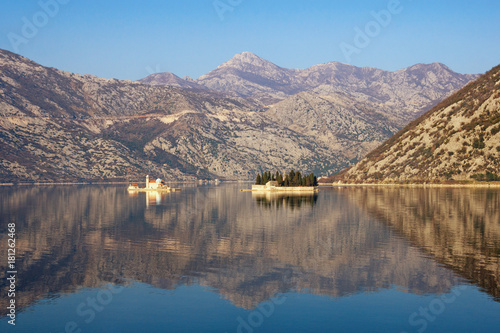 Mountains and two islands of Our Lady of the Rocks and St. George are reflected in the Kotor Bay on a sunny winter day. Montenegro