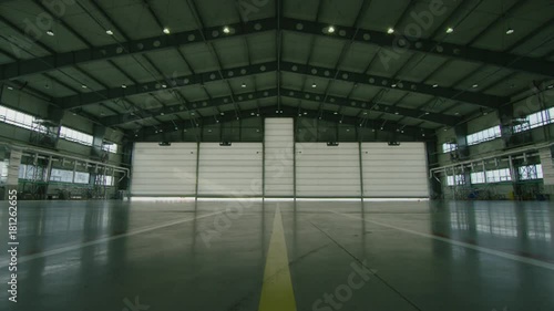 Hangar for aircraft with large open gate at sunny summer day. Large aircraft hangar open the gates photo