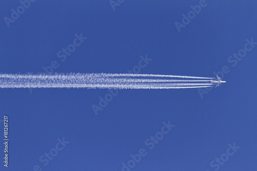 Airplane leaving condensation trails on a clear blue sky. photo