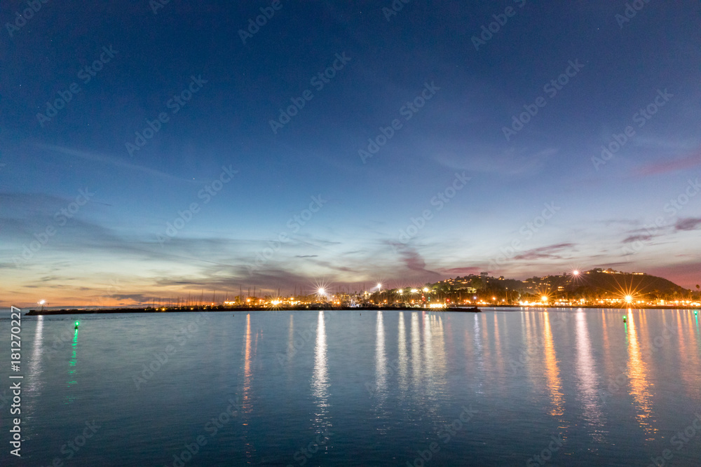 Beautiful night view from the shore over water to a city lights reflected on water in evening