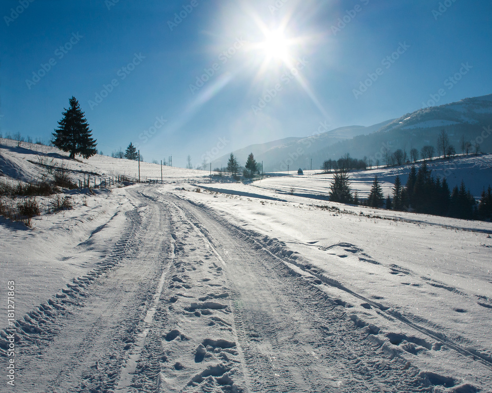 Winter landscape in mountains road on background of blue sky and sun