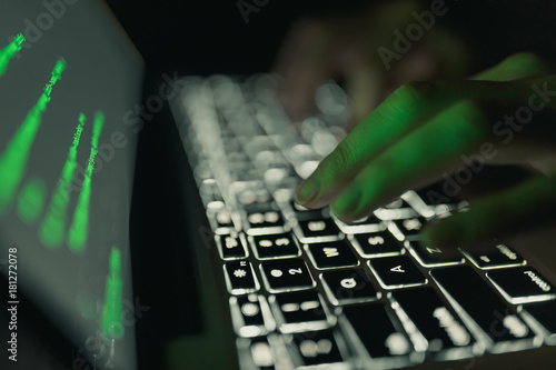 Cyber crime concept: hands of a person hacking on laptop in the darkness