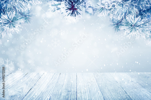 Falling snow on pine tree branches and wooden deck background, copy space
