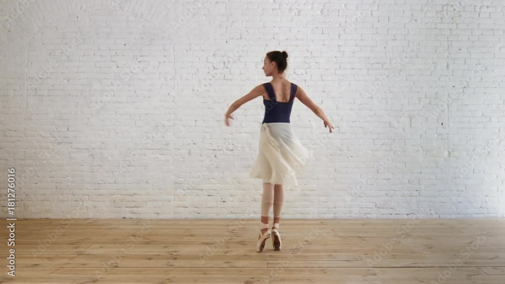 Ballerina performs pirouette in room on the brick wall background Ballerina performs pirouette in room on the brick wall background