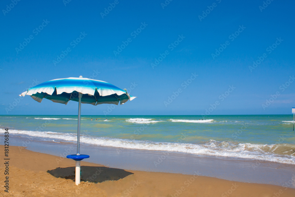 Adriatic Sea coast view. Seashore of Italy, summer umbrellas on sandy beach with clouds on horizon.