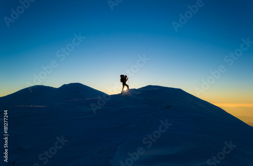 Men silhouette on a background of snowy mountains. Blue sky. Sunset in the Carpathians, Ukraine.