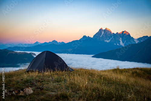 The tent stands on the background of high mountains. Around the wonderful landscape. Evening. Sunset. Tourism in the Caucasian Mountains in Georgia.