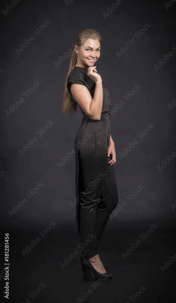 Smiling girl in black suit posing on a dark background. Smiling girl in black suit posing on a dark background.