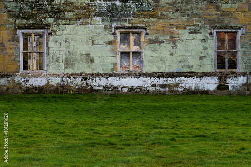 A wall of ruins with green grass in front of it.