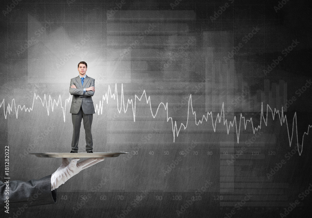 Confident businessman presented on metal tray against graphs and diagrams background Confident businessman presented on metal tray against graphs and diagrams background
