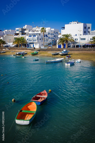 Fototapeta Naklejka Na Ścianę i Meble -  Coloridas barcas flotan en el mar azul con las casas blancas al fondo