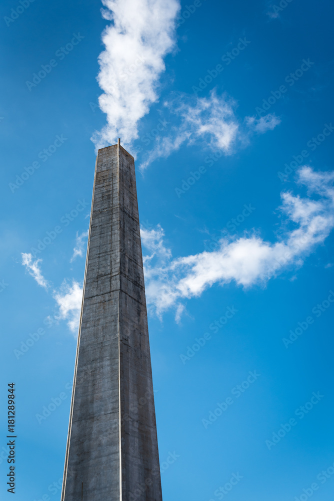 Industrial chimney smoking with blue sky and clouds