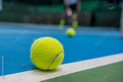 Yellow tennis ball on blue and green hard court surface 