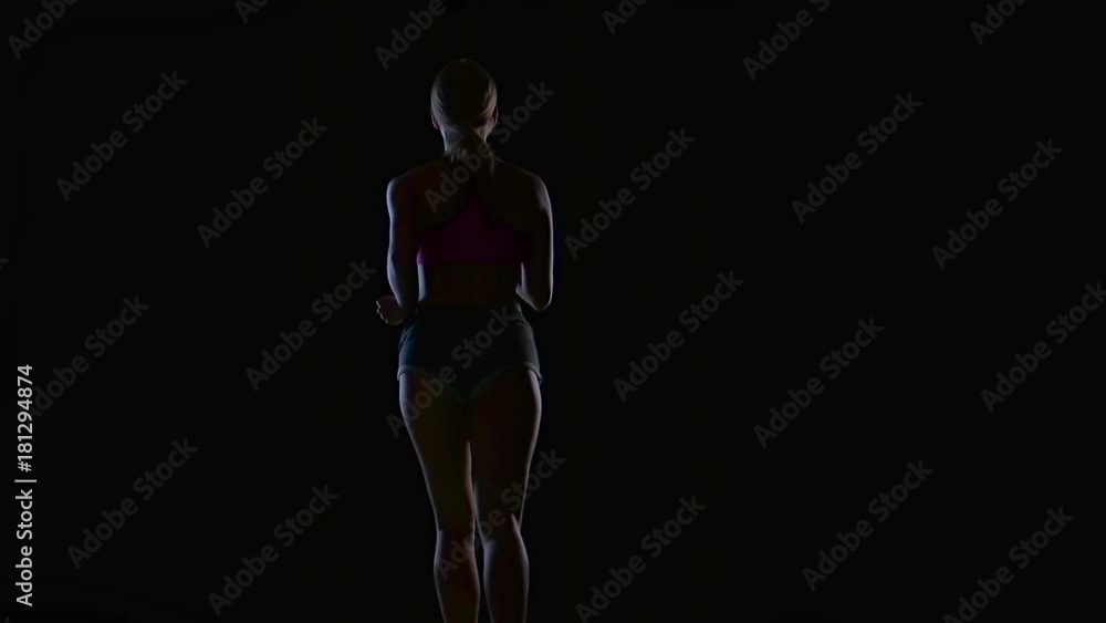 Athletic fitness woman running rear view on a black background. Silhouette. Slow motion Athletic fitness woman running rear view on a black background. Silhouette. Slow motion