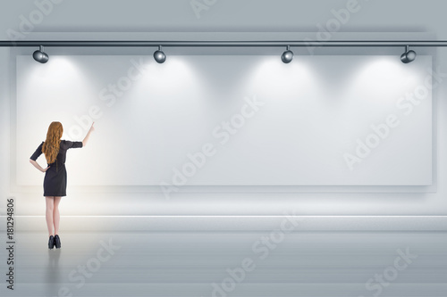 Businesswoman pressing virtual button on the wall lit with spotl photo