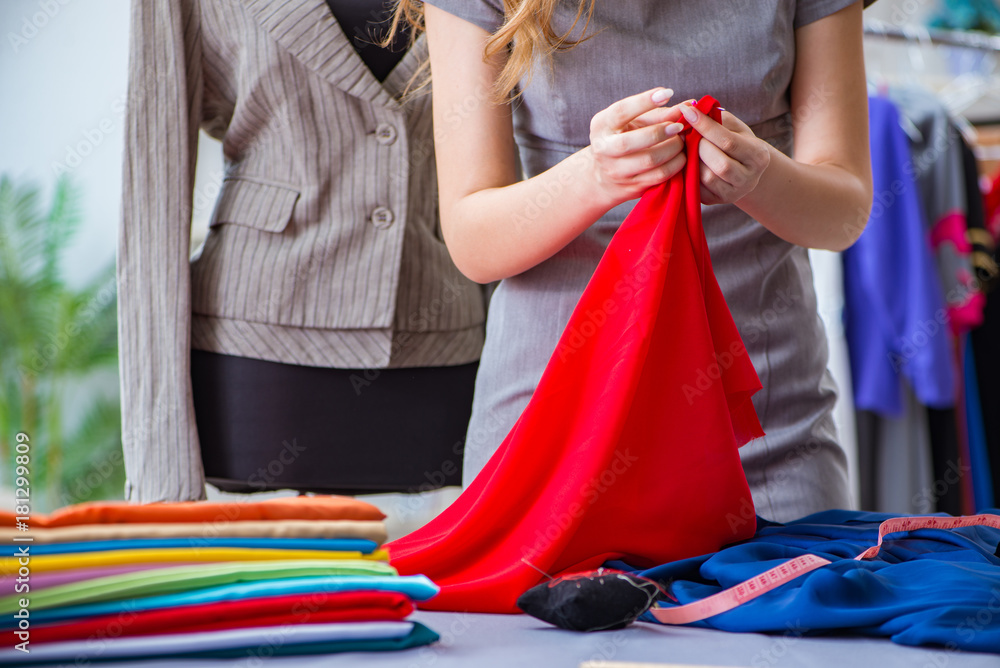 Fototapeta premium Young woman tailor working in workshop on new dress
