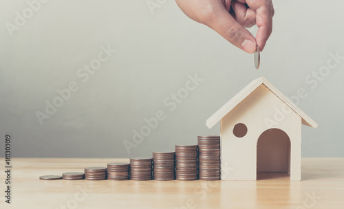 Property investment and house mortgage financial concept, Hand putting money coin stack with wooden house photo