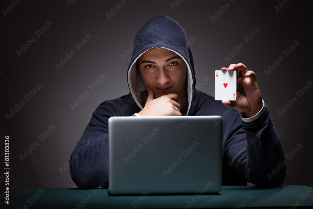 Young man wearing a hoodie sitting in front of a laptop computer Young man wearing a hoodie sitting in front of a laptop computer