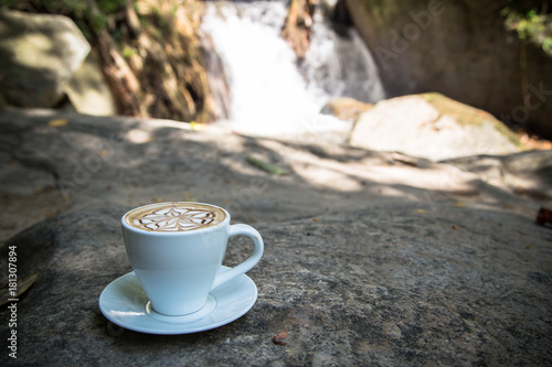 coffee on stone with blur waterfall background