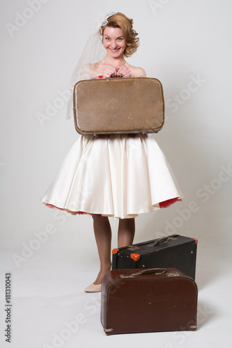 Cheerful bride with suitcases on a light background in the studio. Girl pin up in retro style happy