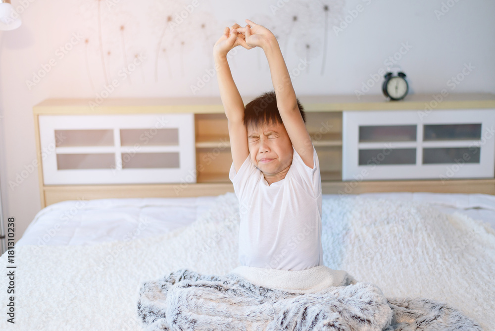 Fototapeta premium Boy waking up in the moring on a white bed.