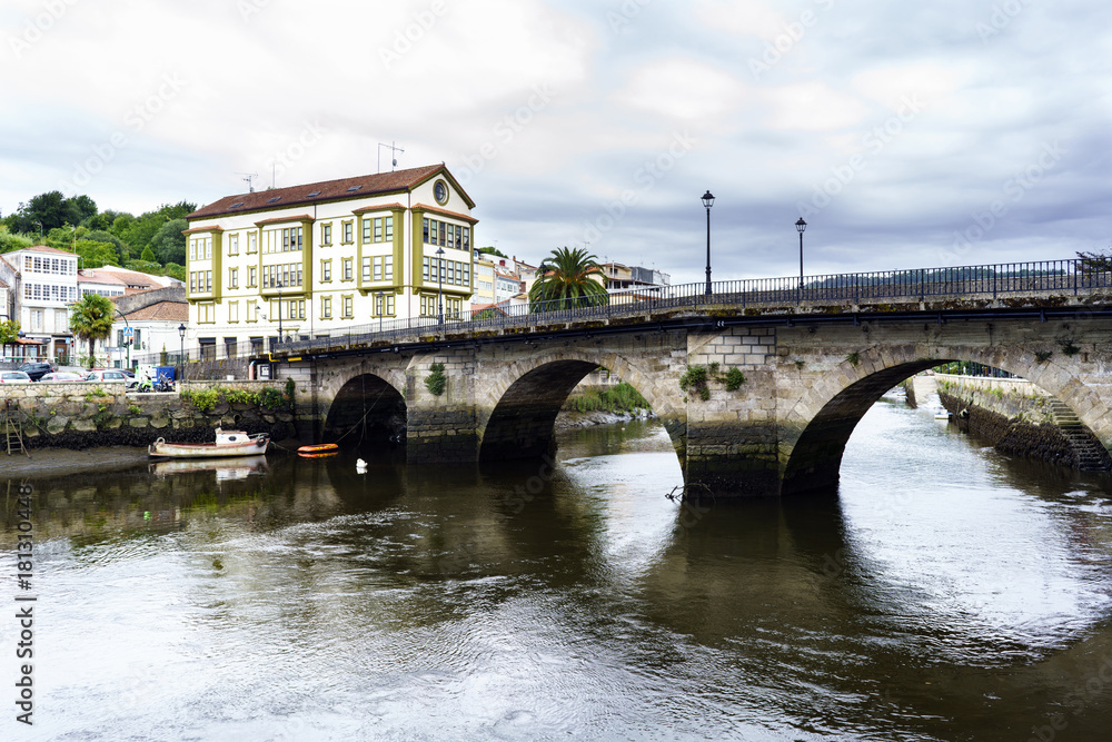 Roman bridge over the Ria de Betanzos with a strong current and in the middle of a town in Galicia, Spain