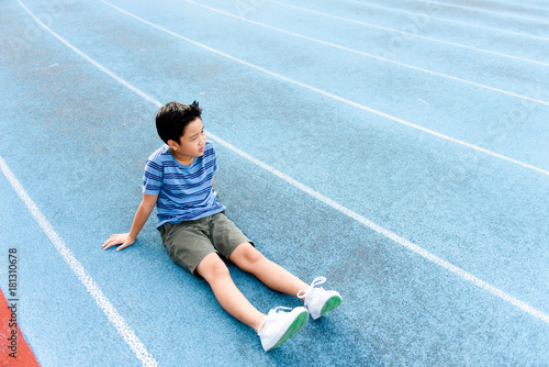 Boy rest on the blue track after sport