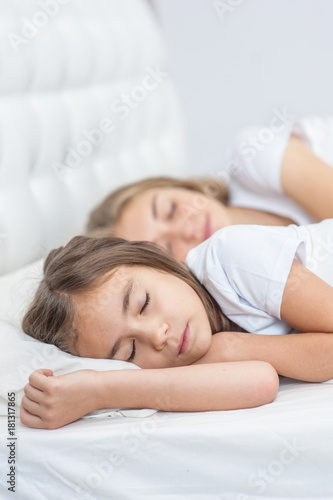 Mom and daughter sleep together on the bed in the bedroom