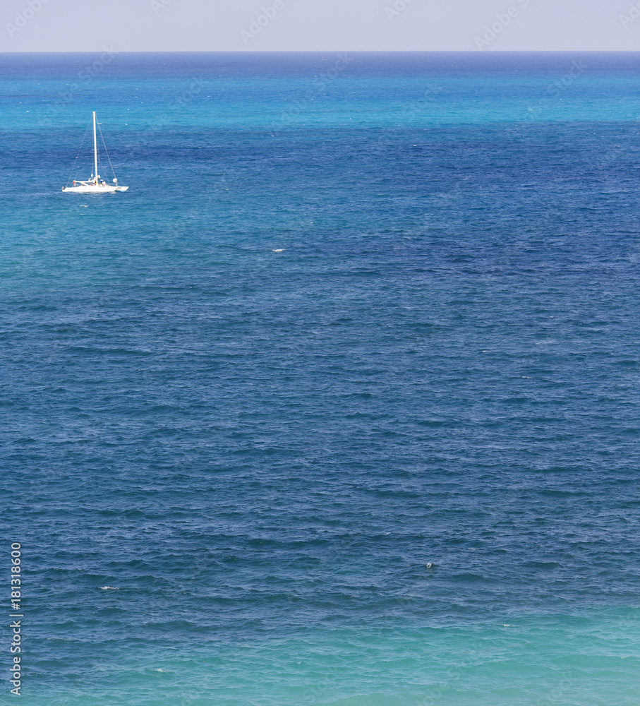 Obraz premium Boat sailing in the middle of the sea. Focus point on the low part of image. Sail boat out of focus.