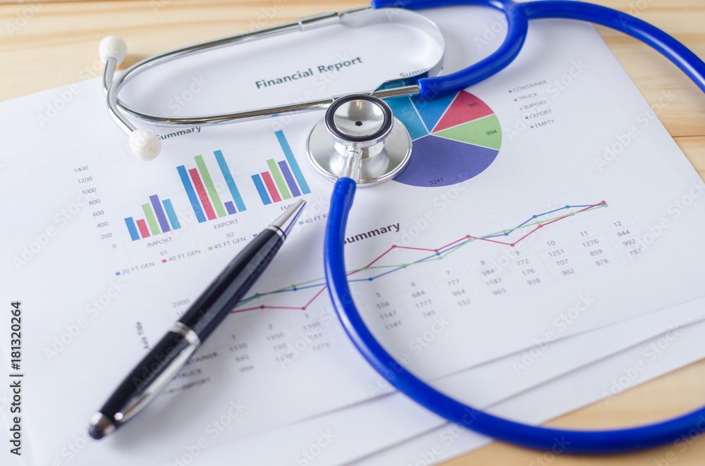 Top view of wooden working table with financial report, stethoscope and pen. Business Concept. Top view of wooden working table with financial report, stethoscope and pen. Business Concept.