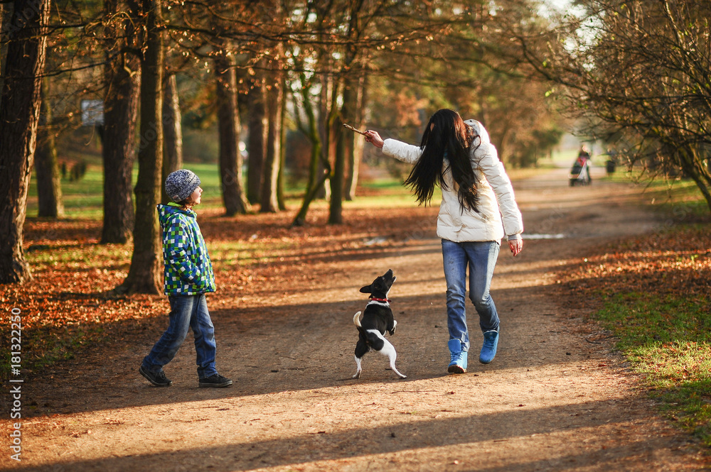 Fototapeta premium Mother and son walk their pet in the autumn Park.