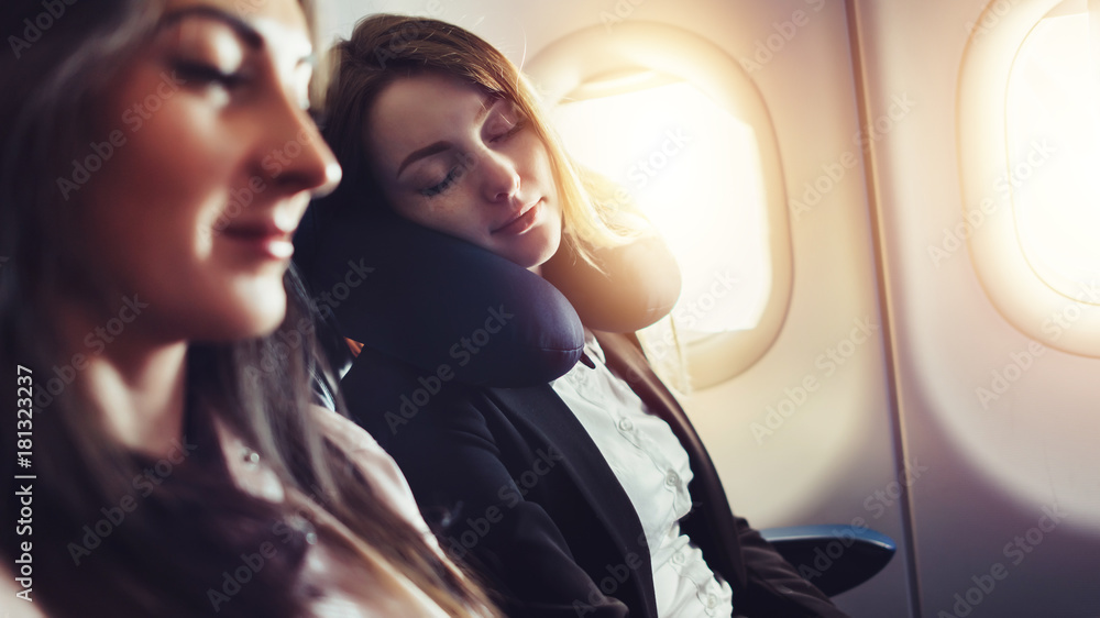 Naklejka premium Dziewczyny podróżujące samolotem. Żeński pasażer śpi na poduszce na karku w samolocie.