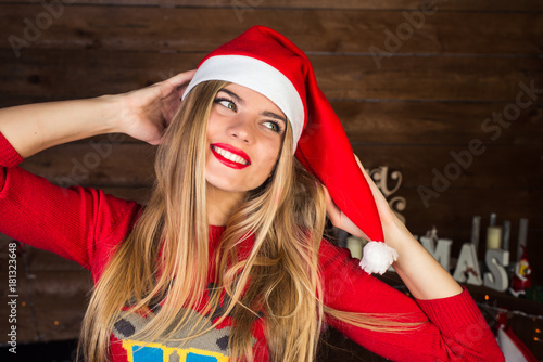 Portrait of attractive girl in Christmas hat in christmas interior. Cheerful and smiling.