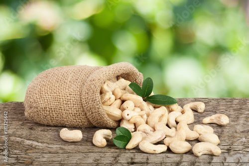 Konstfotografi cashew nuts with leaf in bag on a wooden table with blurred garden background