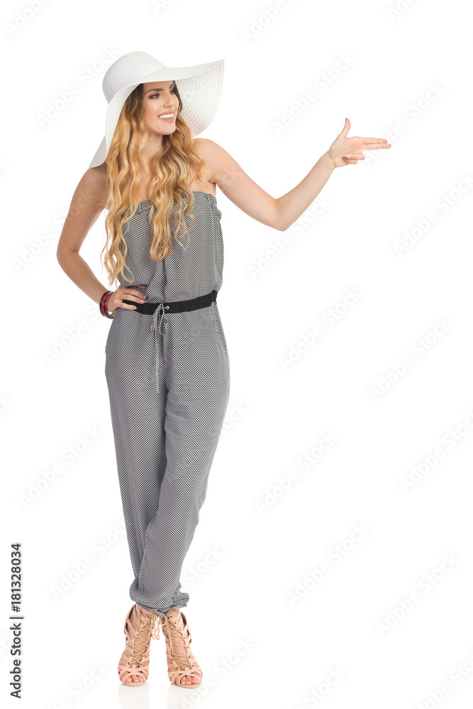 Elegant Young Woman In Sun Hat And Jumpsuit Is Showing Pistol Hand Sign Elegant Young Woman In Sun Hat And Jumpsuit Is Showing Pistol Hand Sign
