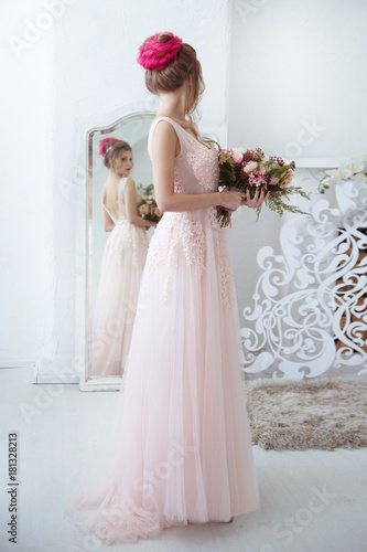Elegant bride with a bouquet in hand in front of a full-length mirror.