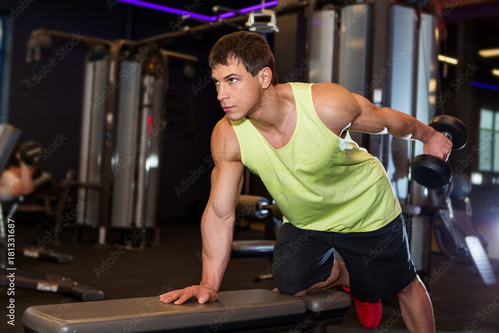 Young man exercising with weight in the gym Young man exercising with weight in the gym