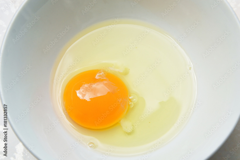 raw yolk and white egg cracked from shell in cup raw yolk and white egg cracked from shell in cup