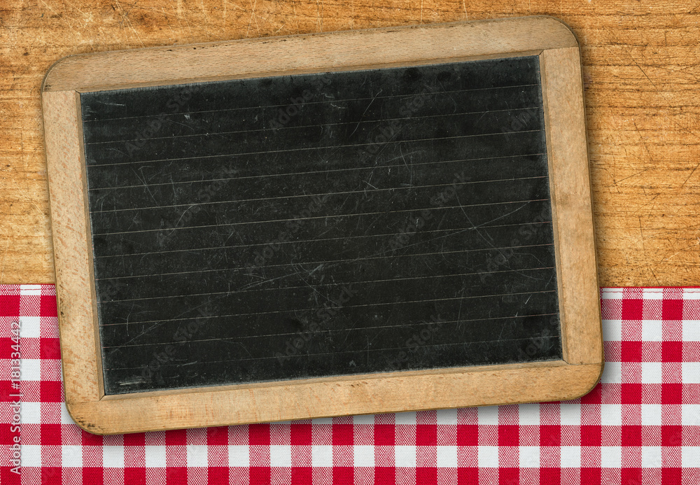 Tafel auf Holzhintergrund mit einem rot karierten Tischtuch Tafel auf Holzhintergrund mit einem rot karierten Tischtuch