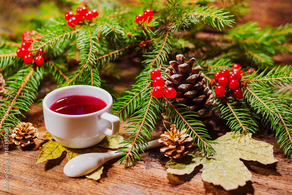 ashberry tea in a white cup. fir branches with rowan on a wooden board. Christmas theme. ashberry tea in a white cup. fir branches with rowan on a wooden board. Christmas theme.